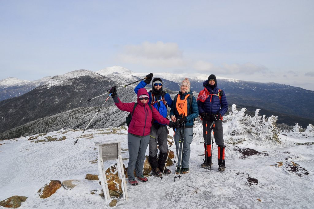 Skiers with trekking poles on the top of a white, snowy mountain.